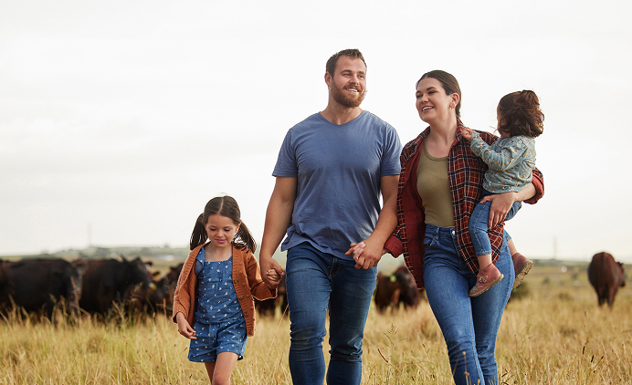 a family walking through a field with cows in the background